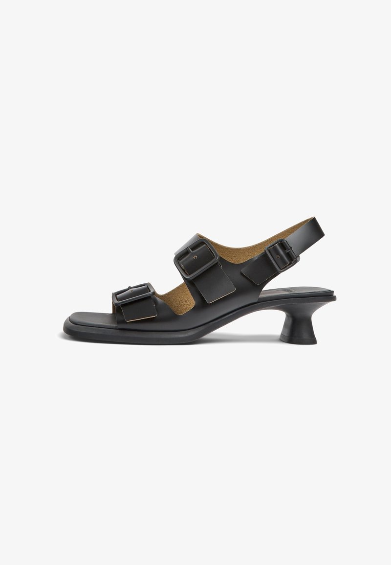 Sandale noire à bout ouvert avec trois brides réglables à boucle, talon bas incurvé et design slingback sur fond blanc.
