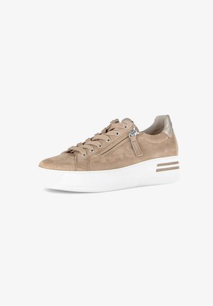 Beige suède sneaker met dikke witte zool, zijrits, beige veters en metalen accenten op de hiel en strepen op de zool.