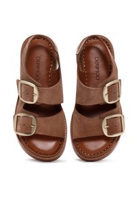 Sandalias de ante marrón con dos correas ajustables y hebillas doradas. Plantillas internas suaves en marrón con una suela texturizada y detalles de costura.