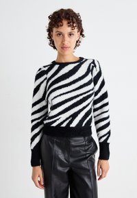 Maglione a righe bianche e nere con una texture morbida, scollatura rotonda e maniche lunghe, abbinato a pantaloni in pelle nera a vita alta.