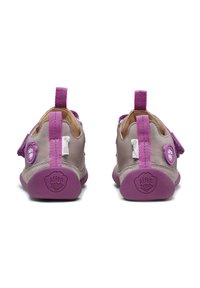 Kinder Schuhe aus hellgrauem Leder mit lila Akzenten, ausgestattet mit einem Klettverschluss, strukturierten Sohlen und Zuglaschen an den Fersen.