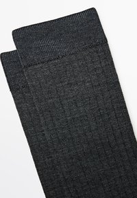 Para ciemnoszarych, prążkowanych skarpetek sięgających do połowy łydki z teksturowanym mankietem, ułożonych na białym tle.
