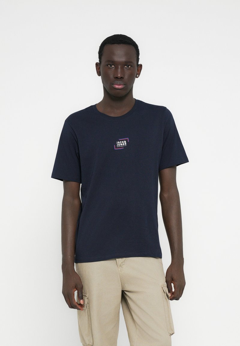 Camiseta de algodón azul marino con mangas cortas y cuello redondo, con un pequeño logo impreso en el pecho. Diseño liso, sin patrones.