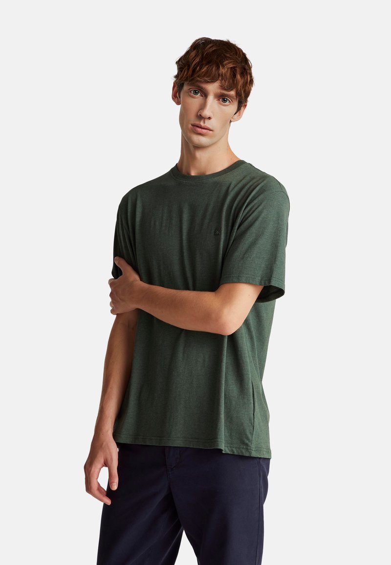 Zelené bavlněné tričko s kulatým výstřihem a krátkými rukávy, s jemným logem poblíž hrudi. Hladká textura a volný střih.