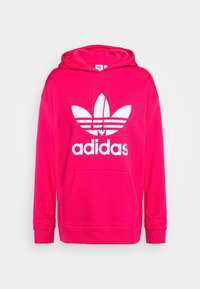 Fuchsia hoodie i bomull, med en stor vit adidas-logotyp med tre ränder och dragsko i huvan. Känguruficka ingår.