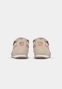 Beige suedestøvler med lyserøde accenter, hvid sål, Velcro-stropper og guld logo detalje på hælen. Bagfra udsigt, der viser design og farver.