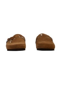 Zapatos de ante marrón, tipo slip-on, con punta redondeada y suela plana. Cuentan con costuras decorativas y un detalle de hebilla en los laterales.