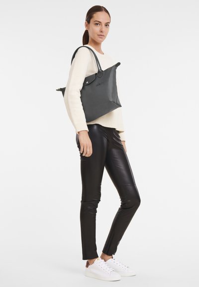 Große schwarze Ledertasche mit strukturiertem Design, ausgestattet mit zwei stabilen Griffen und einem minimalistischen Erscheinungsbild.