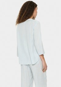 Set di abbigliamento casual a righe azzurro chiaro e crema; top morbido con maniche a tre quarti, orlo curvato e pantaloni abbinati con righe simili.