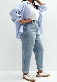 Světle modrá pruhovaná oversized košile, bílý top bez rukávů, světle denimové džíny s vysokým pasem a volnočasové dvoubarevné tenisky. Jednoduchý, uvolněný střih.