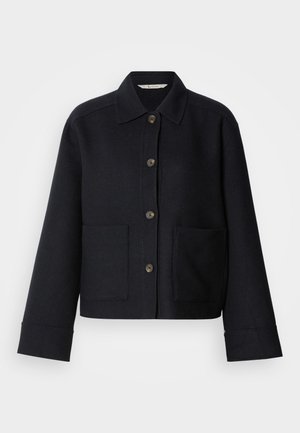 Tume sinine villane jakk, millel on eest nööbitav sulgemine, laialdane krae ja kaks esimest taskut. Lihtne disain lühikese pikkuse ja laiade varrukatega.