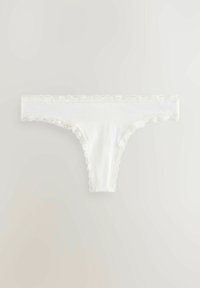 Witte tangaslip met een kantafwerking op de taille en beenopeningen, gemaakt van zacht, glad materiaal met een naadloos ontwerp.