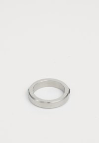 Silver metal ring with beveled edges and small screws on the sides, placed on a white surface.