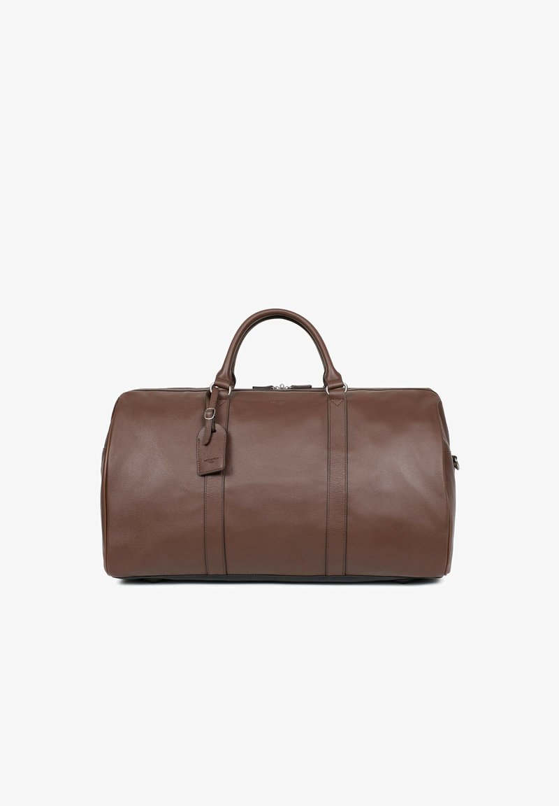 Brązowa skórzana torba podróżna o gładkiej fakturze, z podwójnymi uchwytami u góry, zamknięciem na zamek błyskawiczny i dołączoną metką bagażową. Posiada akcenty w postaci pionowych szwów.