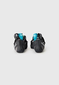 Black climbing shoes with a textured rubber sole, featuring a turquoise strap and branding on the heel and side. Lightweight mesh upper.