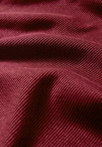 Burgunderfarbener gerippter Stoff mit horizontalen strukturierten Linien, der eine weiche, glatte Oberfläche und einen subtilen Glanz aufweist. Ideal für verschiedene Textilanwendungen.