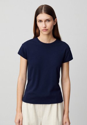 T-shirt bleu marine à manches courtes avec un col rond, texture lisse et coupe légèrement décontractée, associé à un pantalon à rayures claires.