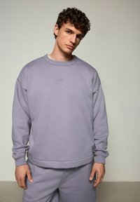 Lila sweatshirt met geribde manchetten en ronde hals; heeft subtiele geborduurde logo. Gecombineerd met bijpassende sweats. Zachte textuur, ontspannen pasvorm.