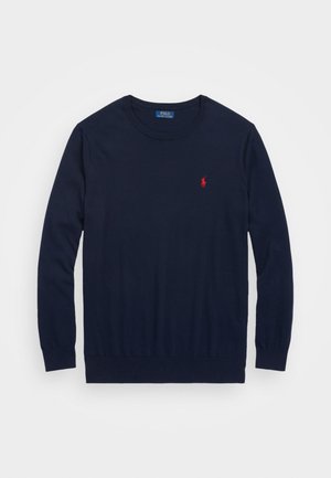 Mörkblå crewneck-tröja av mjukt tyg, med långa ärmar och en röd broderad logotyp på bröstet. Ribbat halsringning och ärmslut.