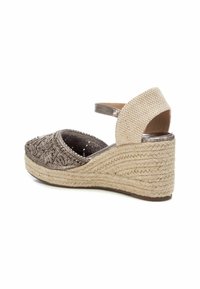 Sandalia cuña con un upper de bronce metálico, patrón bordado y una plataforma de yute trenzado. Cuenta con una correa en el tobillo de color marrón claro con un acabado texturizado.