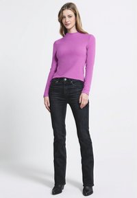 Maglietta viola aderente a maniche lunghe realizzata in un tessuto liscio, abbinata a jeans neri a gamba dritta con un classico design a cinque tasche.