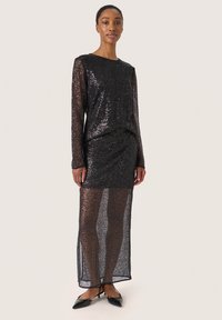 Schwarzes Paillettenkleid mit langen Ärmeln, eng anliegendem Oberteil und einem transparenten, bodenlangen Rock. Das Material hat eine schimmernde Textur und einen geraden Schnitt.
