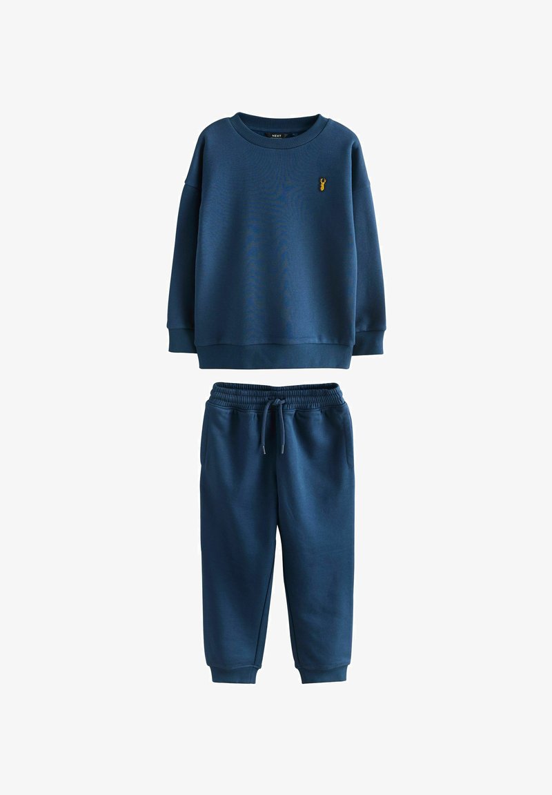 Sweat-shirt bleu marine et pantalon de jogging assorti avec taille et poignets élastiques, présentant un petit logo cerf jaune sur la poitrine.