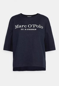 Námořnická modrá bavlněná tričko s krátkým rukávem, s bílým textem "Marc O'Polo EST. V STOCKHOLMU" na přední straně. Standardní design s kulatým výstřihem.
