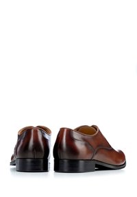 Brązowe skórzane buty formalne o wypolerowanej powierzchni, okrągłym nosku, minimalnym przeszyciu i niewielkim obcasie. Gładka tekstura, czysty design.