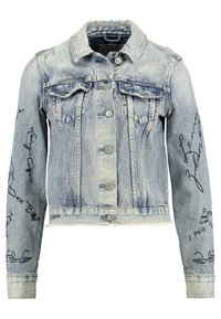 Ljusblå jeansjacka med två bröstfickor, knäppningar och uppvikta ärmar. Har klottrat svart text och mönster på ärmarna.