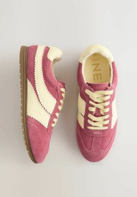 Adidași din piele întoarsă roz și crem, cu partea superioară texturată, cusături zigzag contrastante și talpă de cauciuc cu un design ușor.