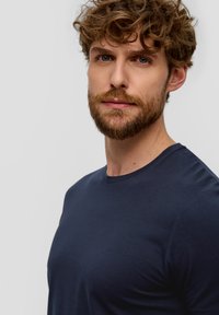 Maglietta a maniche corte blu navy realizzata in morbido cotone, collo rotondo e design aderente, che mette in mostra una superficie liscia.