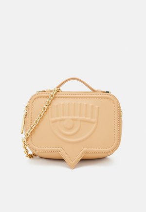 Sac à main en simili cuir beige avec design embossé d'un œil, bandoulière chaîne dorée et fermeture éclair. Forme rectangulaire structurée avec une base plate.