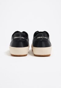 Sneaker in pelle nera con suola in gomma crema, dotate di colletto posteriore imbottito e ricamo del marchio "BIMBA Y LOLA".