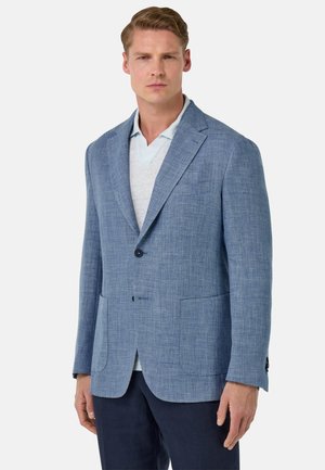 Hellblaues Blazer aus strukturiertem Stoff, mit einem einzelnen Knopfverschluss, Reverskragen und zwei vorderen Taschen. Wird über einem hellen Polo getragen.