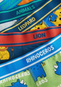 Farverigt børnetøj med forskellige dyremønstre og elastiske taljebånd mærket "LØVE," "NASHORN," "LEOPARD," og "DYR."
