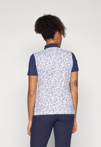 Kurze Ärmel Polohemd mit einem marineblauen Kragen, das ein weißes, strukturiertes Muster aufweist. Hergestellt aus glattem Stoff, hat es ein tailliertes Design und einen abgerundeten Saum.