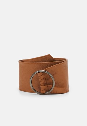 Large ceinture en cuir marron avec surface texturée et grande boucle métallique ronde, affichée enroulée sur fond blanc.