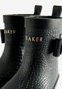 Tuvumā melni gumijas lietus zābaki ar krokodila tekstūru un "BAKER" etiķeti. Divas cilpas augšā, lai tos būtu viegli uzvilkt.
