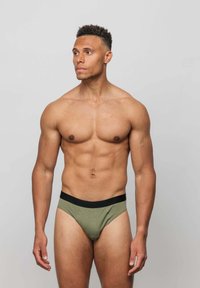 Herren-Unterwäsche in Olivgrün aus weichem Stoff mit einem schwarzen elastischen Bund, bietet eine enge Passform und ein minimales Design.