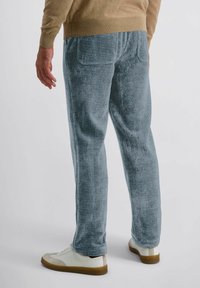 Grijze corduroy broek met verticale ribbels, met een achterzak. Gecombineerd met beige schoenen, met een rechte pijp en een zachte textuur.