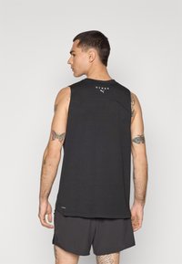 Zwart mouwloos sporttop met een ronde halslijn, voorzien van een logo op de achterkant en een licht gebogen zoom. Gelaagd materiaal.