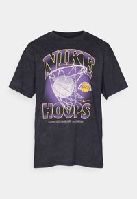 Čierne bavlnené tričko s veľkým grafickým designom "NIKE HOOPS" v purpurovej a žltej farbe, obsahujúce motív basketbalovej lopty a siete, s logom Los Angeles Lakers.