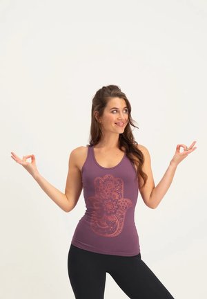 Lila Tanktop mit einem detaillierten orangen Handgrafik, aus weichem Material, kombiniert mit schwarzen, figurbetonten Leggings. Glatte Struktur, ärmelloses Design.