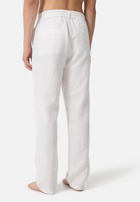 Witte linnen broeken met een elastische tailleband, met een relaxte pasvorm en twee achterzakken, weergegeven vanuit het achteraanzicht.