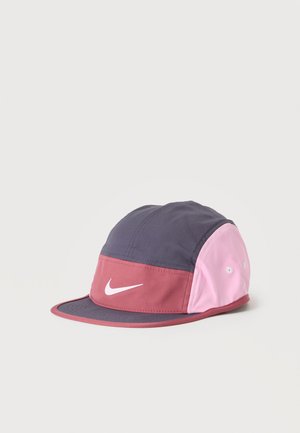 Gorra deportiva estilo cap con parte superior gris oscuro, paneles laterales rosas, banda frontal roja, logo blanco de Nike y visera plana sobre fondo liso.