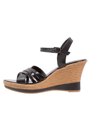 Sort kilehæl sandal med flettet stråplatform, krydsede blanke remme og justerbar ankelrem med spænde.