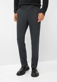 Donkergrijze op maat gemaakte broek met een gladde textuur, platte voorkant en subtiel patroon, gecombineerd met zwarte veterschoenen.