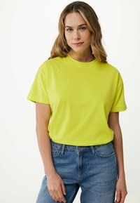 Neon žluté tričko s krátkým rukávem a kulatým výstřihem. Měkká tkanina, volný střih, v kombinaci s modrými džínami. Jednoduchý, jednobarevný design.
