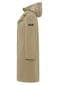 Beige nepbontjas met een gewatteerde, glanzende capuchon. Heeft een enkele sluiting en zijzakken. Logo-label op de mouw.